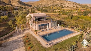 A modern villa with a pool, surrounded by hills and vegetation. - Villa Dama - Luxury Escape (Avola)