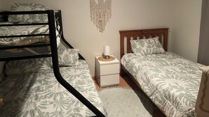 A dorm-style room with bunk beds, a bedside table with a lamp, and a macrame wall hanging. - Elliston Esplanade Beach House (RUFF-INN-IT) (Elliston)
