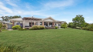 Ein zweigeschossiges Haus mit einer überdachten Terrasse und einem gepflegten Rasen.