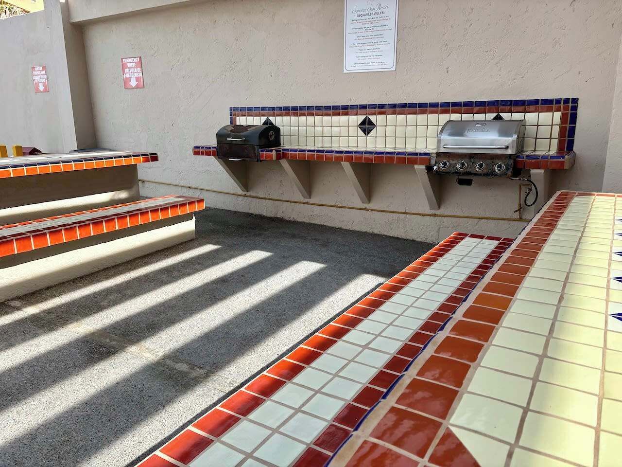 A tiled outdoor area with a grill and a mailbox.