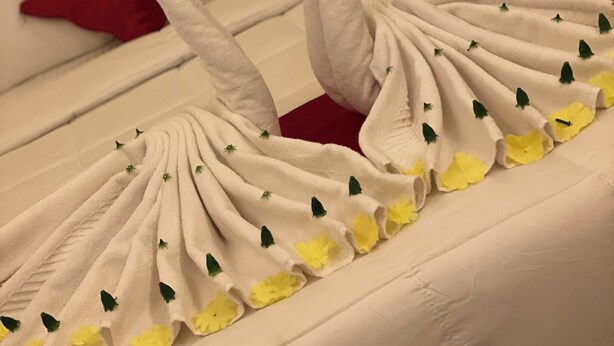 Ein Bett mit weißer Bettdecke und einer dekorativen Schwanen-Handtuch-Arrangement.