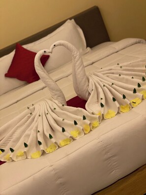 Ein Bett mit weißer Bettdecke und einer dekorativen Schwanen-Handtuch-Arrangement.