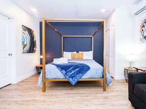 Una cama con dosel de cuatro postes, almohadas blancas y una colcha azul.