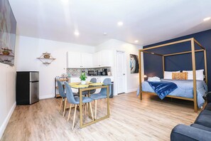 A compact living space with a dining area, kitchenette, and a bed with a canopy.
