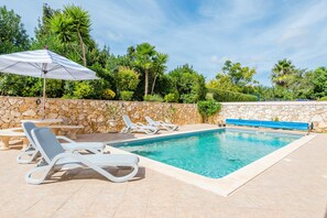 A swimming pool with white lounge chairs and a stone wall. - Casa Rosa at Boavista Resort (Lagos)