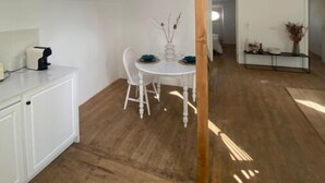 Une pièce spacieuse dotée d’une lucarne, de poutres apparentes, d’une table à manger avec des chaises et d’un buffet blanc.