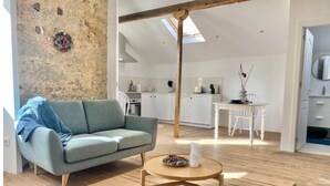 Un salon moderne avec un canapé, une table basse et une cuisine en arrière-plan.