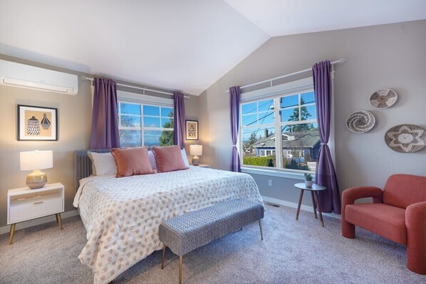 A bedroom with a bed, bedside tables, a bench, a chair, and a window with curtains. - Fremont home with panoramic views near Woodland Zoo (Seattle)