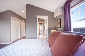 A bedroom with a large bed, a walk-in closet, a window with curtains, and a view of the city. - Fremont home with panoramic views near Woodland Zoo (Seattle)