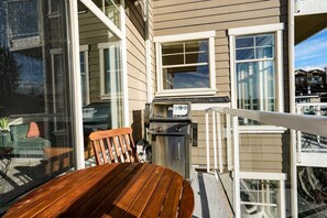 A wooden deck with a table and chairs, a barbecue grill, and a glass door leading to a living area. - Fremont home with panoramic views near Woodland Zoo (Seattle)
