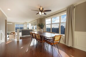 A spacious dining area with a wooden table and leather chairs, large windows with a city view, and a ceiling fan. - Fremont home with panoramic views near Woodland Zoo (Seattle)
