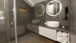 Une salle de bain moderne avec une douche à parois de verre, un miroir rond, un lavabo et un porte-serviettes.