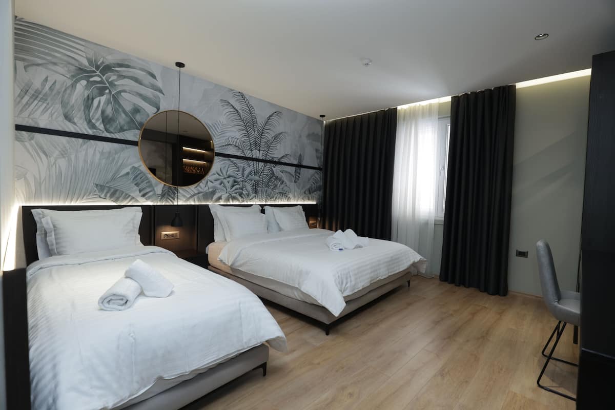 A modern hotel room with two beds, a large mirror, and a wall mural.