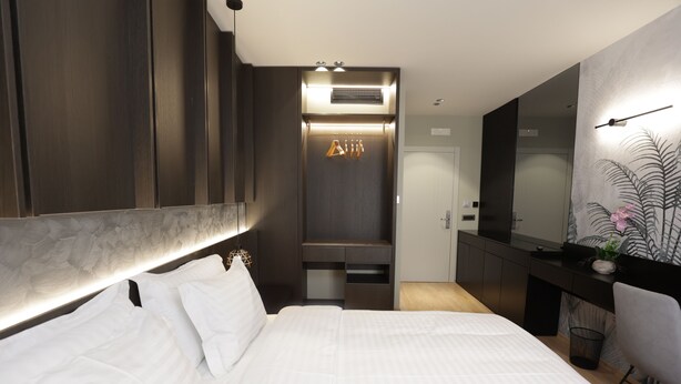 Une chambre d’hôtel moderne dotée d’un grand lit, d’un bureau intégré, d’un miroir et d’un espace douche.
