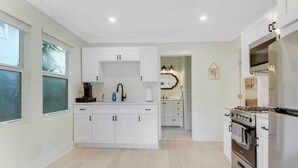 Una cocina moderna con armarios blancos, una estufa de acero inoxidable y un ventanal grande.