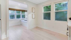 Una habitación amplia con ventanas grandes, un banco empotrado y una paleta de colores neutros.