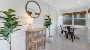 Una habitación con una mesa de comedor y sillas, un espejo redondo y dos plantas en macetas.