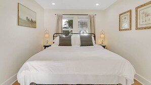 Una cama bien hecha con sábanas blancas y dos almohadas, flanqueada por mesitas de noche con lámparas.