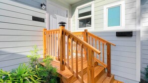 A wooden staircase leading to a porch with a mailbox and a small window. - Cottage on Croton Way # 2 (West Palm Beach)