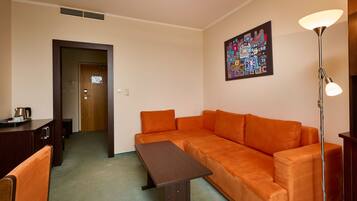 Um quarto com um sofá marrom, uma mesa de madeira, um abajur e um quadro na parede.