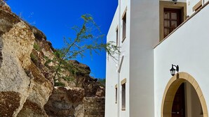A white building with a stone pathway leading to an arched entrance. - Litois Houses Patmos (Patmos)