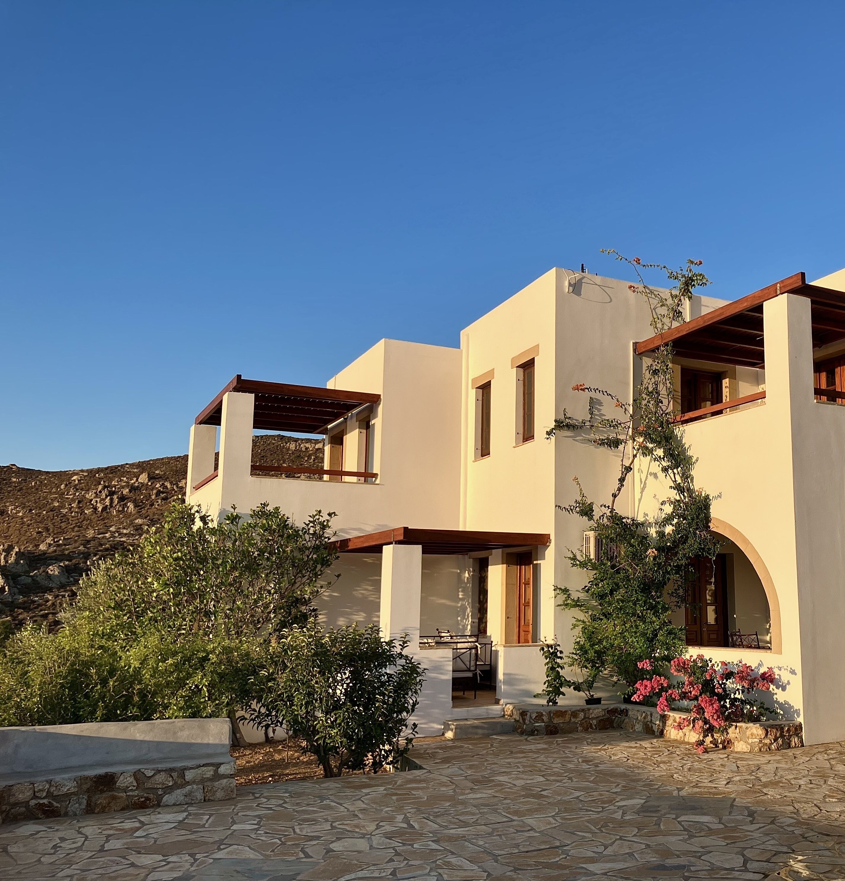 Una casa moderna de dos pisos con entrada empaveda de piedra, un porche cubierto y vistas a un paisaje montañoso.