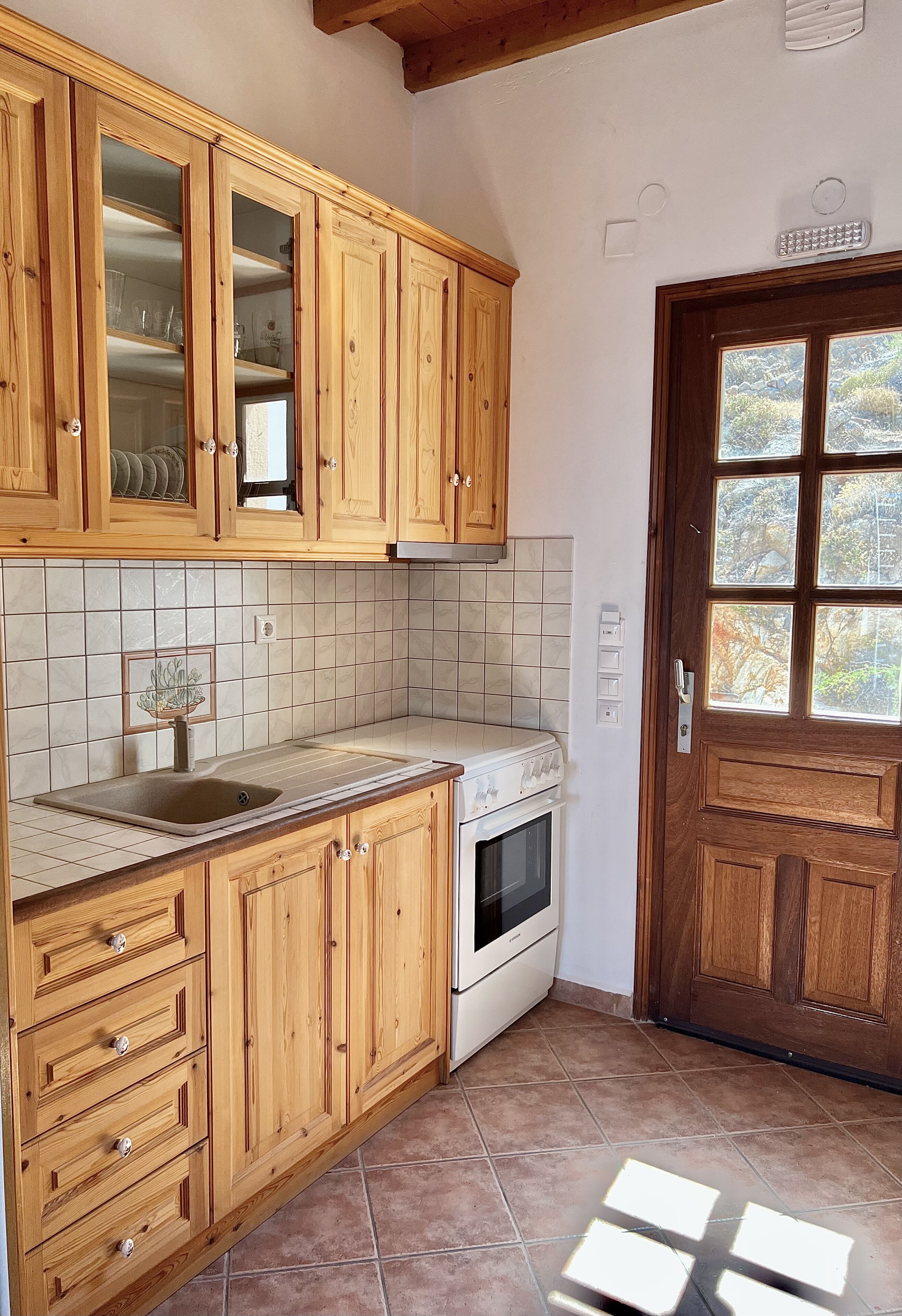 Una cocina con armarios de madera, salpicadero de azulejos, un lavabo y una estufa.