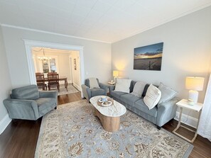 Una sala de estar con un sofá, sillones, una mesa de centro y un comedor con sillas y una mesa.