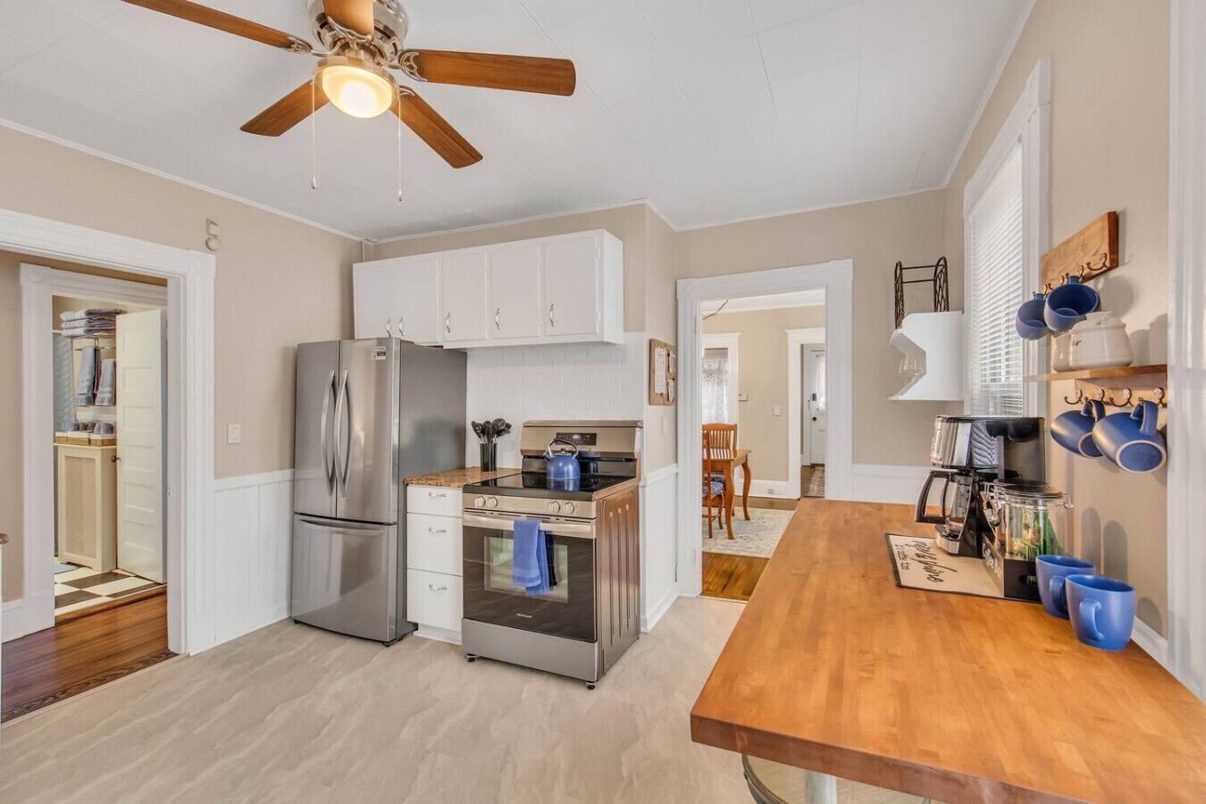 A modern kitchen with stainless steel appliances, a wooden dining table, and a ceiling fan.