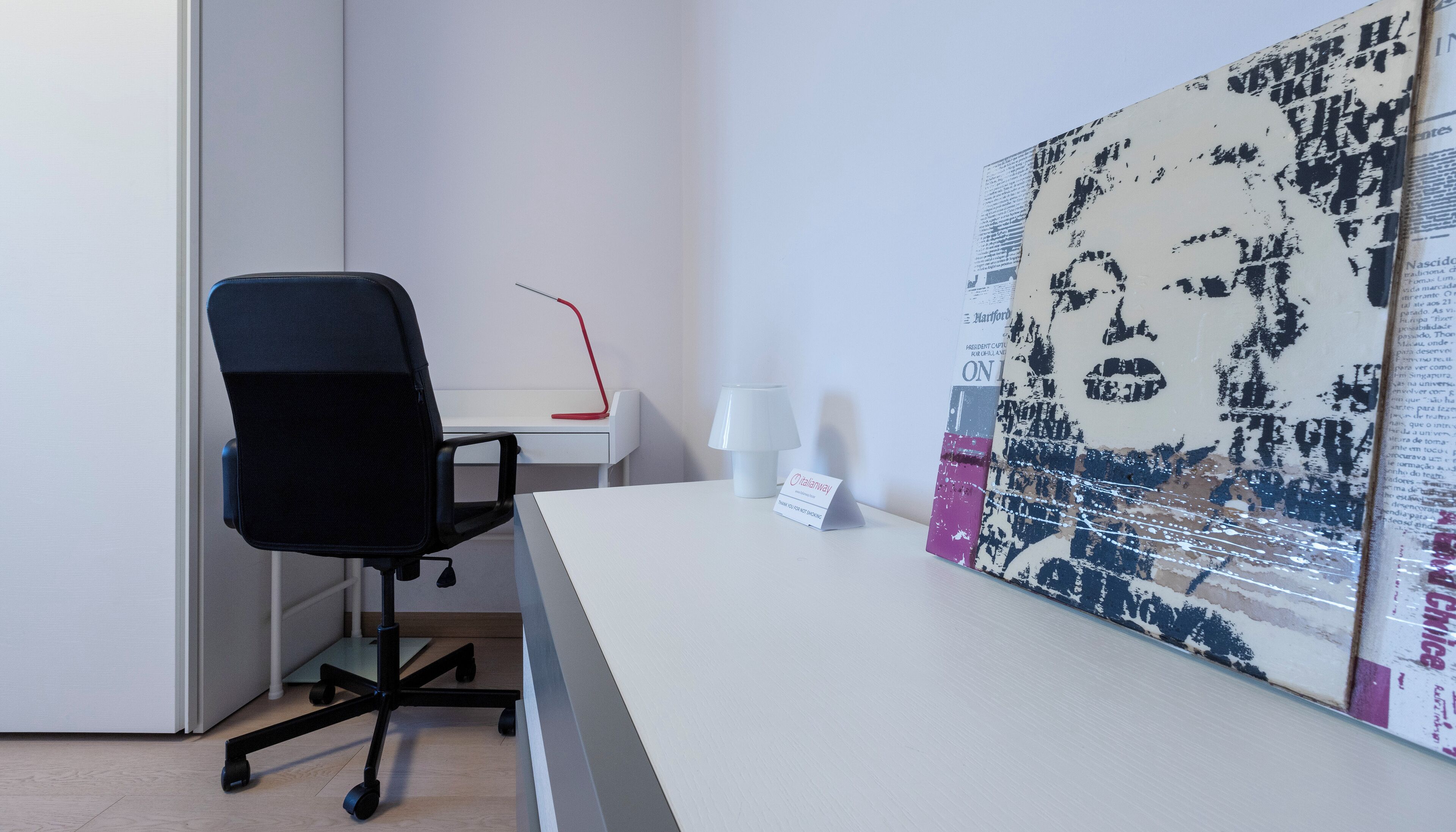 A modern office space with a desk, chair, and a large abstract painting on the wall.