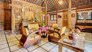 A rustic room with wooden furniture, a brick wall, and a high ceiling with exposed beams. - Hotel O Omah Baturan Syariah (Colomadu)