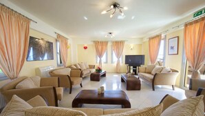 Un salón amplio con sofás color beige, una mesa de centro y un televisor de pantalla plana.
