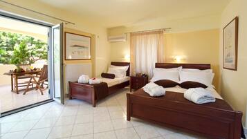 Quarto de hotel com duas camas, área de refeições com mesa e cadeiras, e vista através de uma porta de vidro.