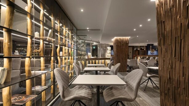 Un intérieur moderne avec un espace salon central, des cloisons en verre et des éléments décoratifs en bois.