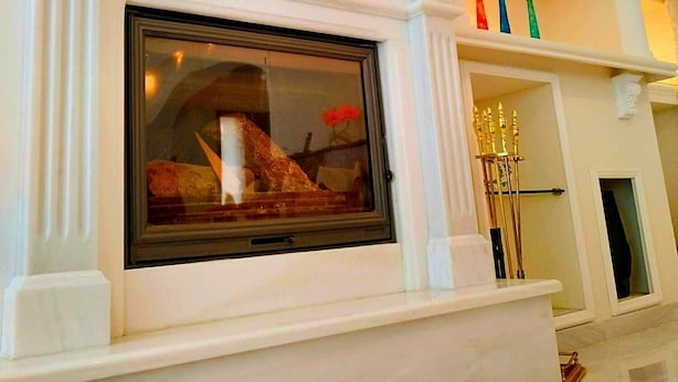 Uma lareira imponente com uma grande janela de vidro, colunas de mármore branco e teto decorativo.