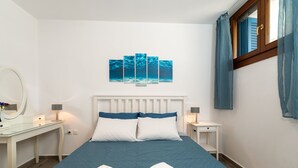 A hotel room with a bed, two bedside tables, a mirror, and artwork on the wall. - Olivia's Countryside House (Paros)