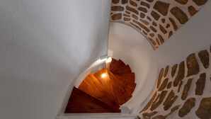 A spiral staircase with a stone wall pattern on the right side. - Olivia's Countryside House (Paros)