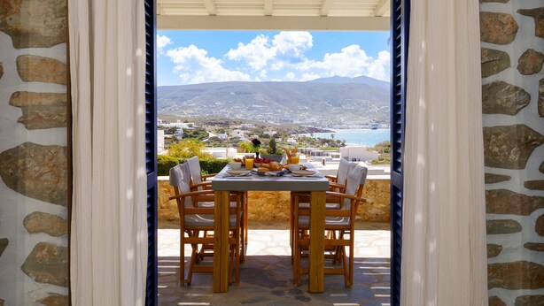 A table set for breakfast with a view of a coastal landscape. - Olivia's Countryside House (Paros)