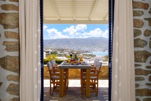 A table set for breakfast with a view of a coastal landscape. - Olivia's Countryside House (Paros)