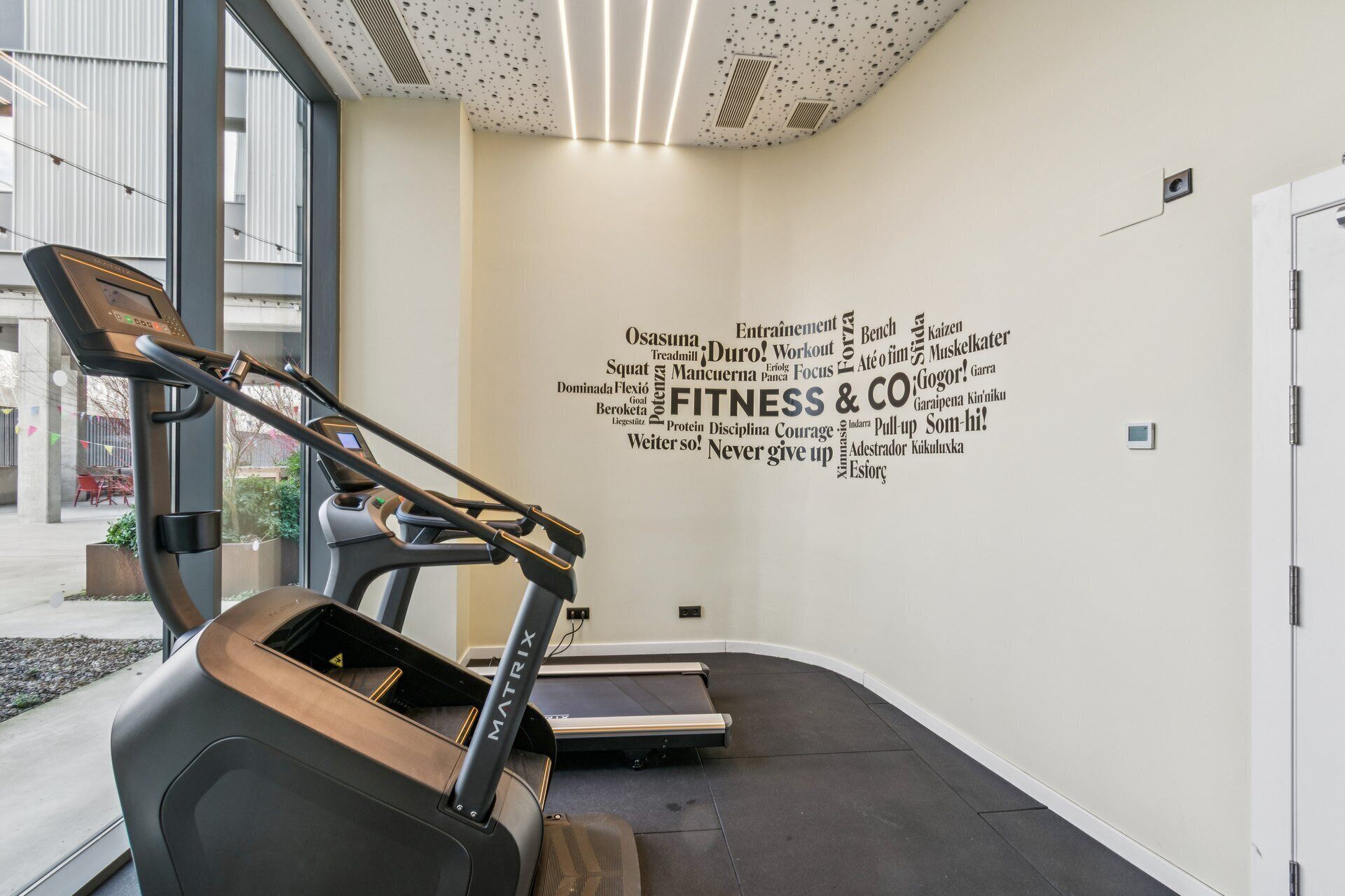 Un espace dédié à la remise en forme, équipé de tapis de course et d’un mur orné de citations motivantes sur le thème du sport et de la santé.