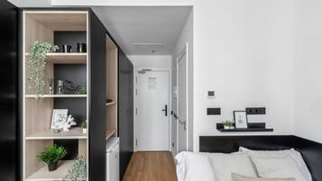 Un dormitorio moderno con cama, armario empotrado y mesita de noche con lámpara.