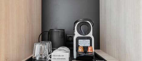 Eine Kaffeemaschine, ein Wasserkocher und eine Ablage mit Gläsern sowie ein Schild auf einem Holzregal.