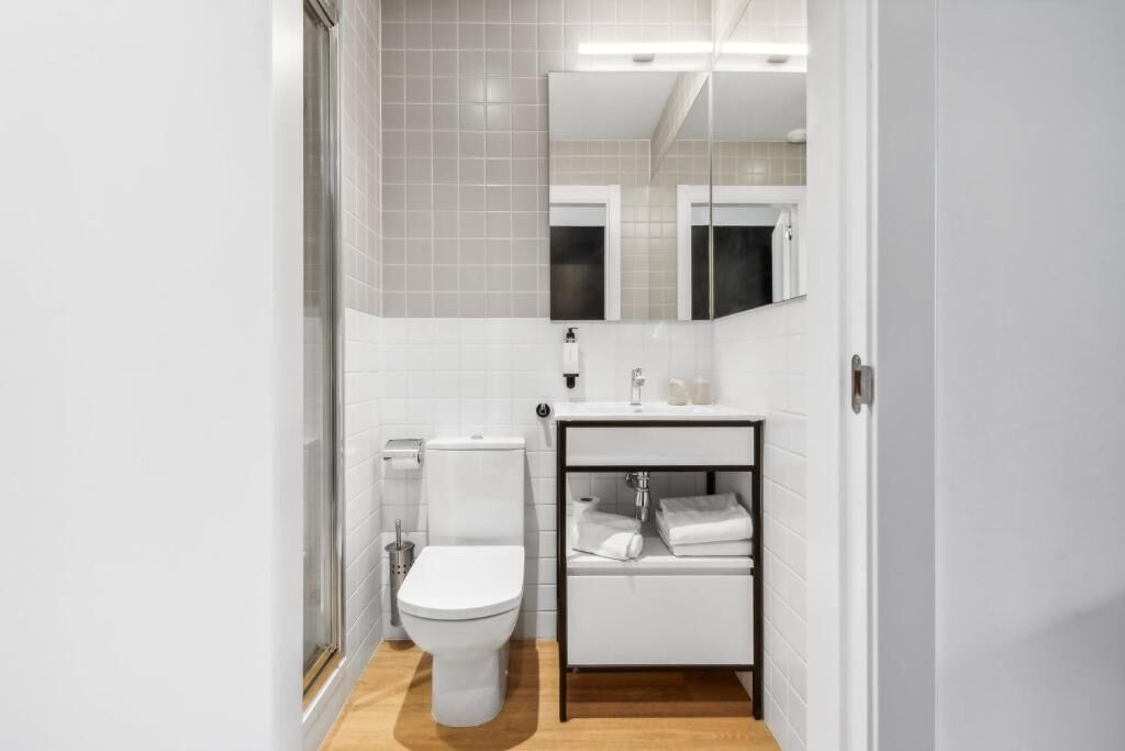 A modern bathroom with a toilet, sink, and mirror.