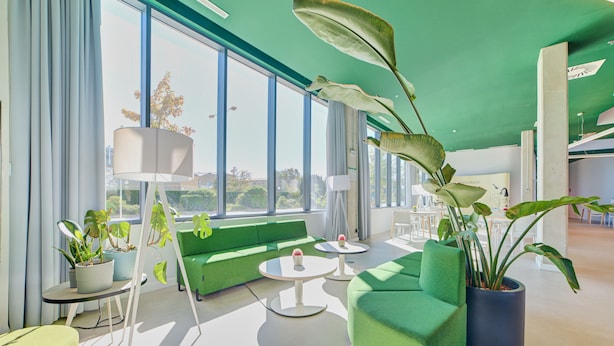 Uma sala de estar moderna com sofás verdes, uma mesa de centro e plantas em vasos.
