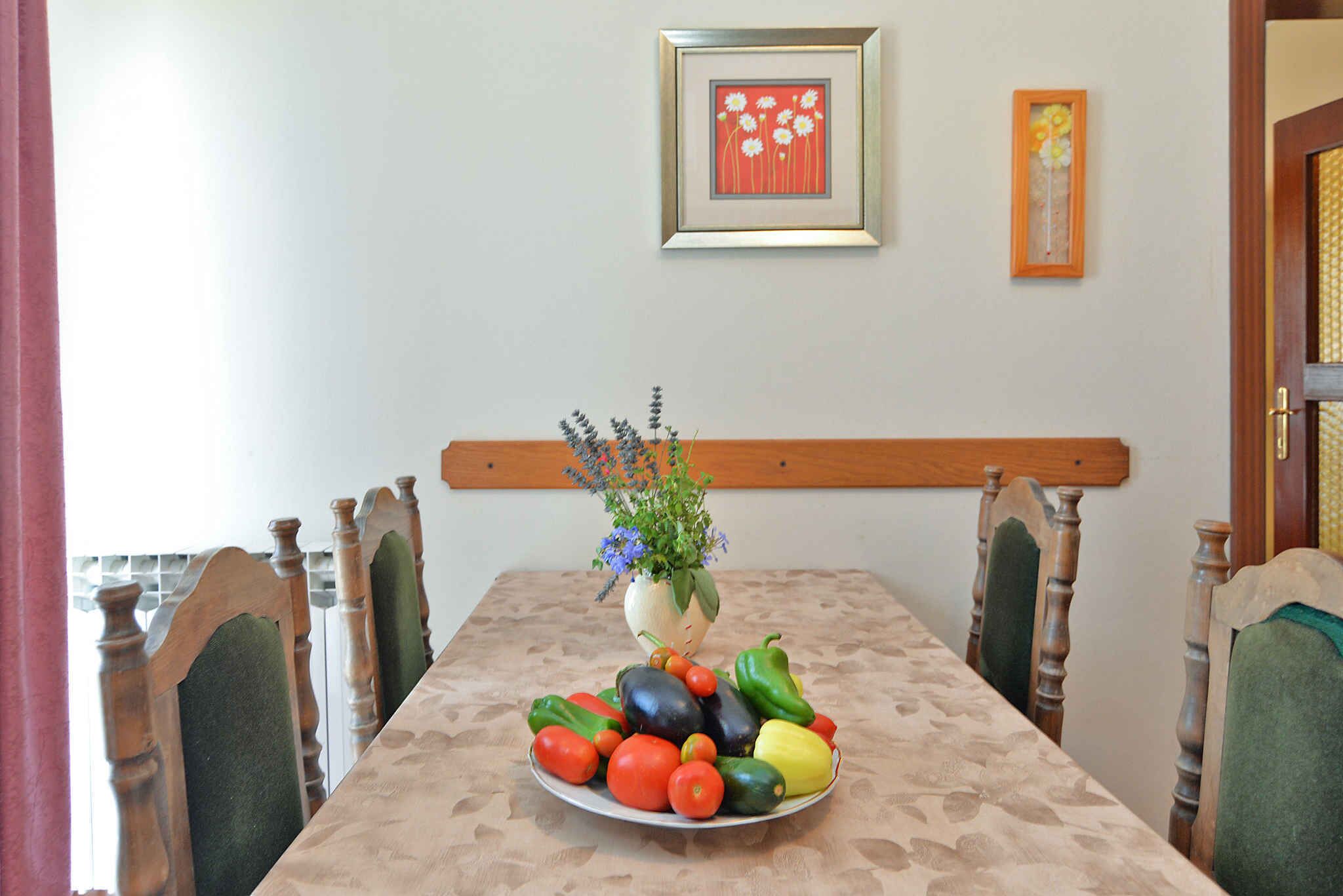Una mesa de comedor con un plato de verduras y un jarrón de flores.
