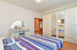 A bedroom with a bed, a dresser, a mirror, and a wardrobe.