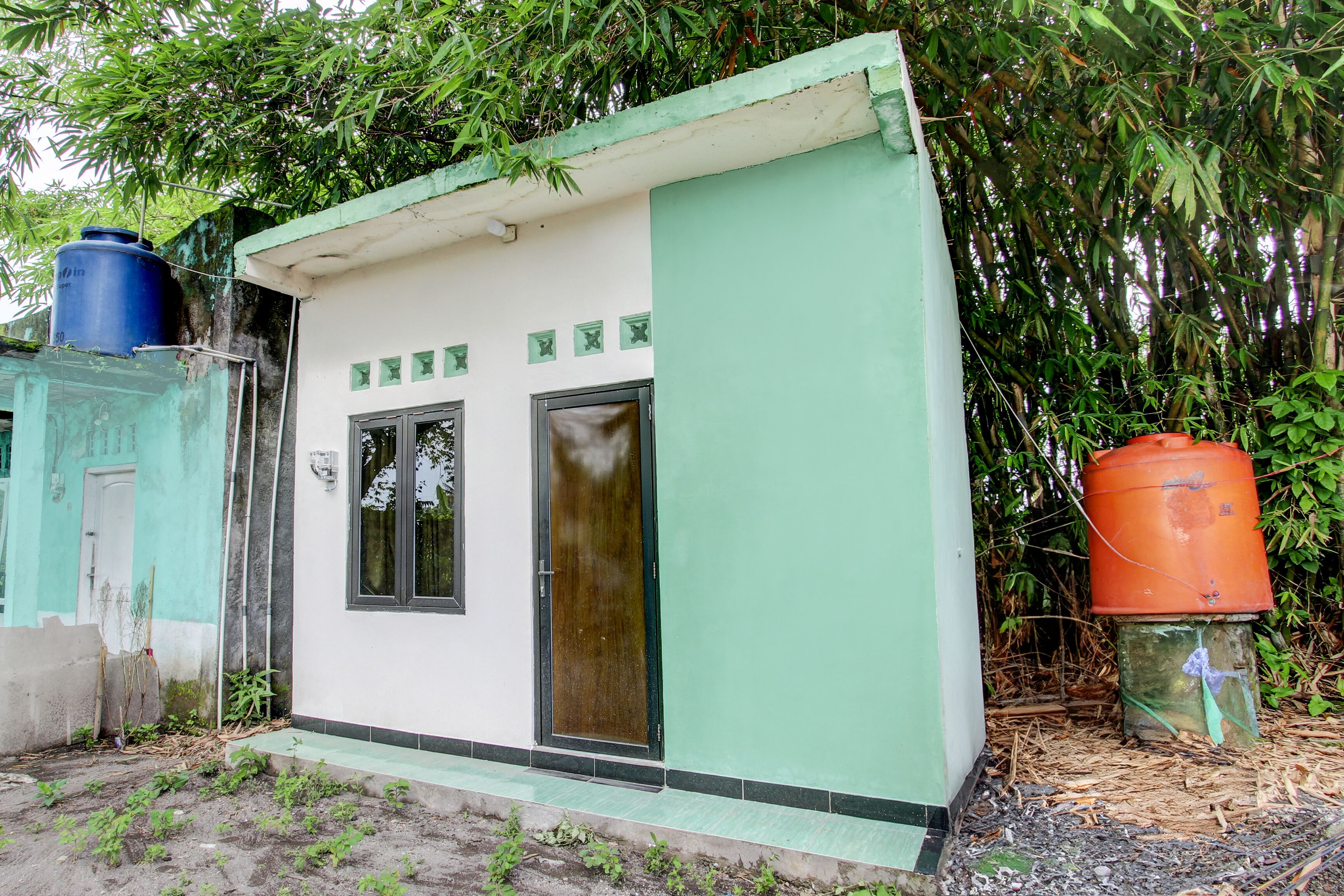 A small, single-story building with a green and white exterior, two windows, and a door.