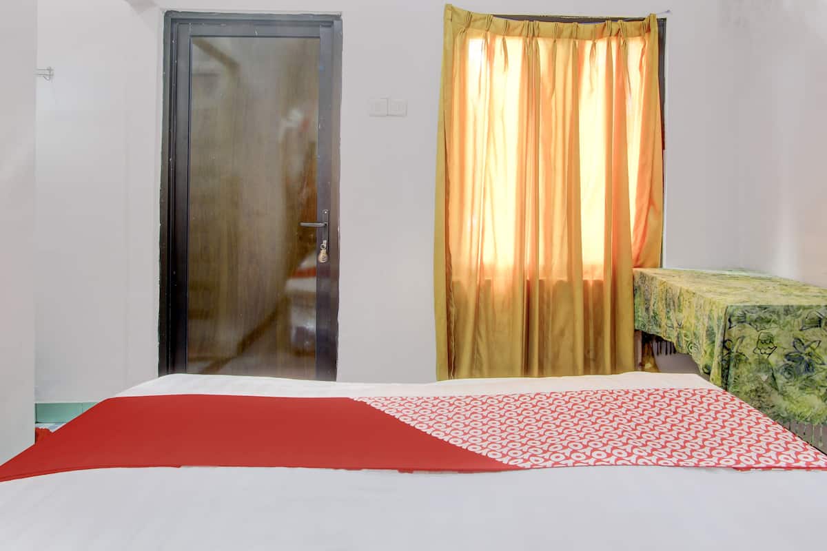 A room with a bed, a door, and a window with curtains.