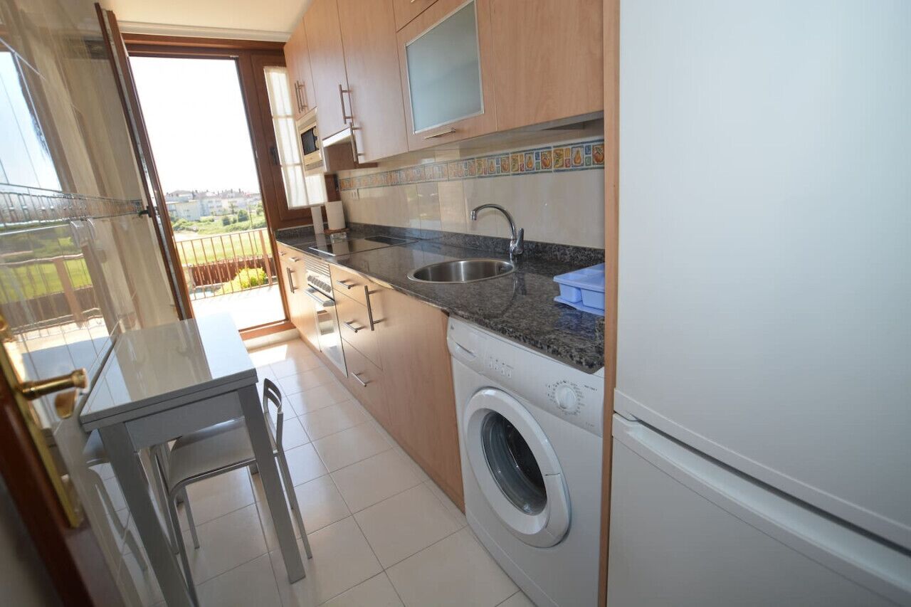 A compact kitchen with a washing machine, a sink, and a small table.