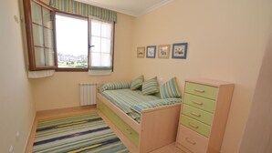 Ein Schlafzimmer mit einem Bett, einem Heizkörper, einem Fenster und einem Schminktisch.